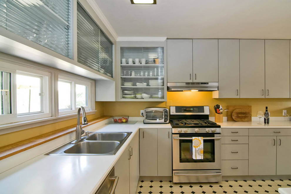 Photo of a large contemporary l-shaped kitchen pantry in San Francisco with a double-bowl sink, glass-front cabinets, grey cabinets, yellow splashback, stainless steel appliances, ceramic floors, no island and multi-coloured floor.