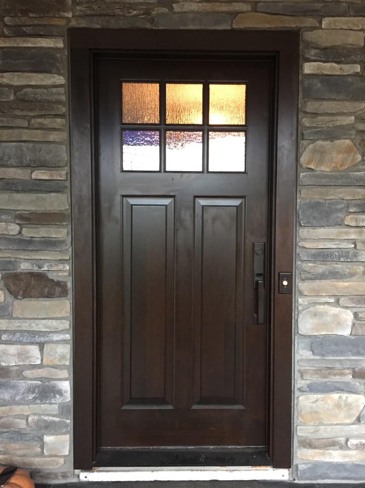 This is an example of an arts and crafts entryway in New York with a single front door and a dark wood front door.