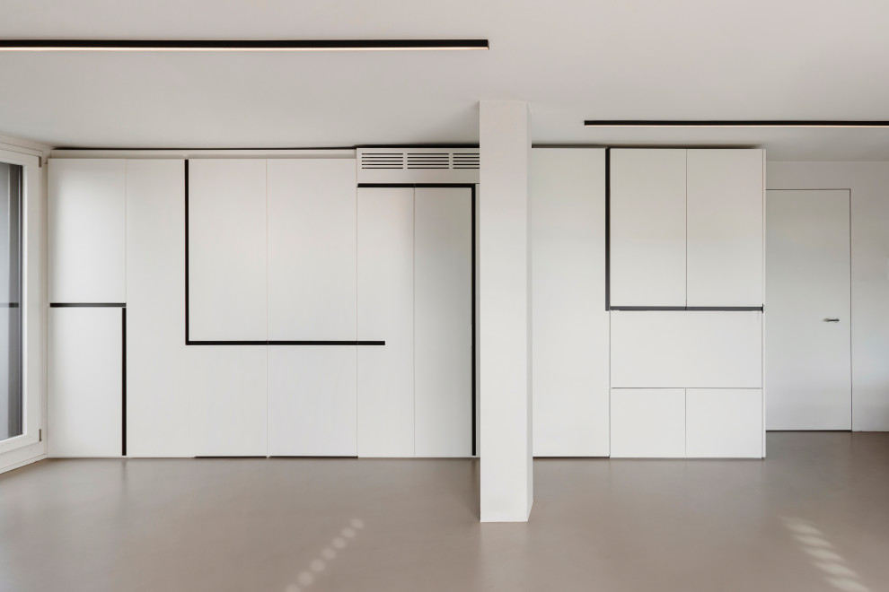На фото: домашняя мастерская среднего размера в современном стиле с белыми стенами, бетонным полом, горизонтальным камином, фасадом камина из металла, встроенным рабочим столом, серым полом и многоуровневым потолком с