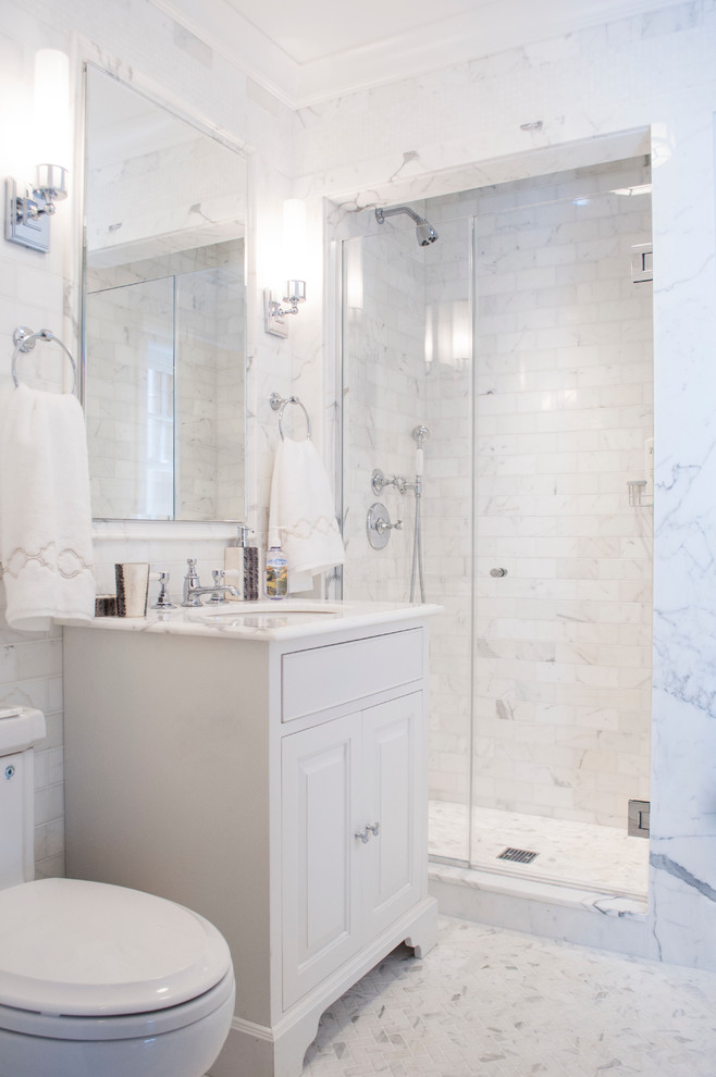 This is an example of a beach style bathroom in New York with an undermount sink, raised-panel cabinets, white cabinets, an alcove shower, a two-piece toilet, white tile and mosaic tile floors.