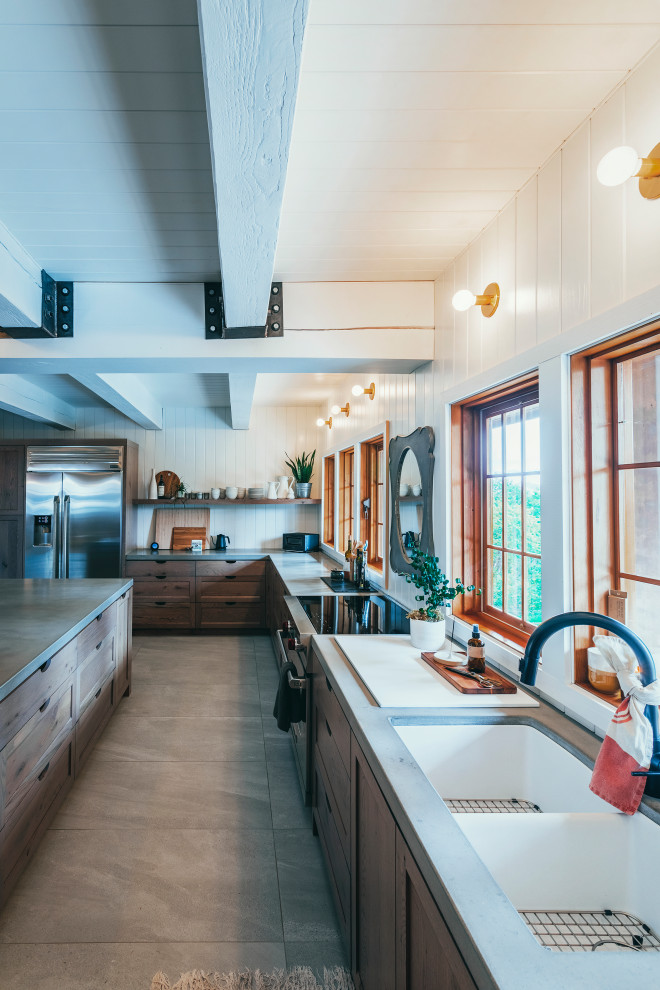 Photo of an expansive country l-shaped eat-in kitchen in Vancouver with an undermount sink, shaker cabinets, medium wood cabinets, concrete benchtops, white splashback, shiplap splashback, stainless steel appliances, porcelain floors, with island, beige floor, grey benchtop and timber.