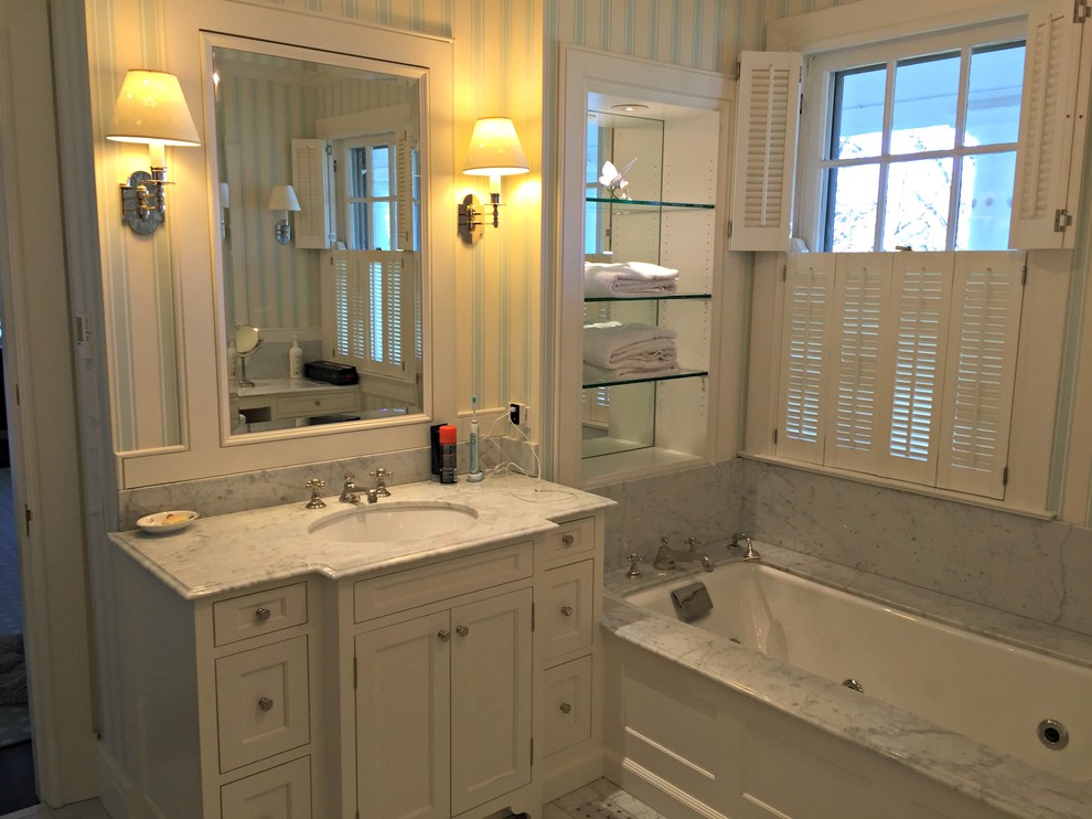 This is an example of a large traditional master bathroom in Cincinnati with shaker cabinets, white cabinets, an alcove tub, white tile, stone tile, multi-coloured walls, marble floors, an undermount sink and marble benchtops.