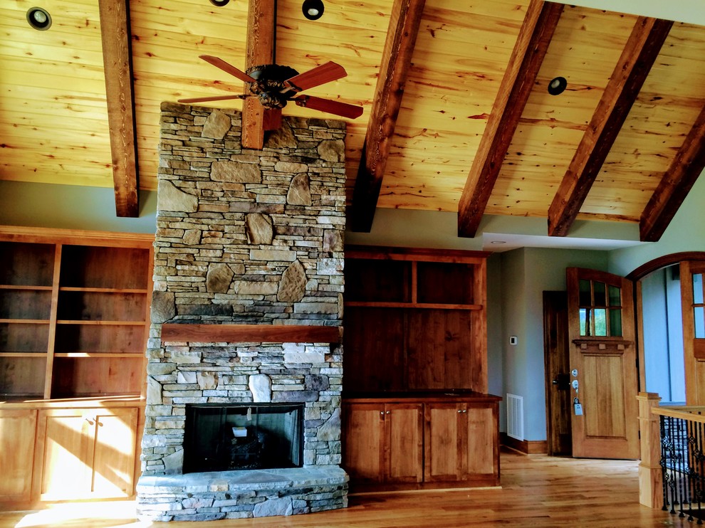 Example of a mountain style open concept medium tone wood floor home design design with a standard fireplace and a stone fireplace