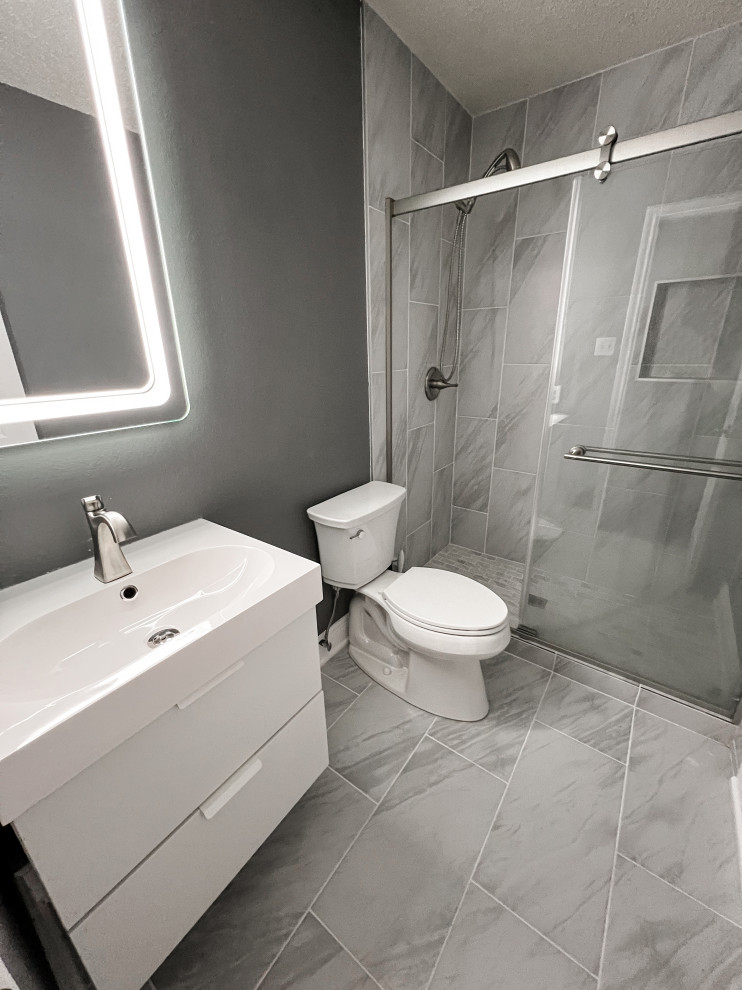 This is an example of a small modern 3/4 bathroom in Austin with flat-panel cabinets, white cabinets, gray tile, grey walls, grey floor, white benchtops, a niche, a single vanity and a floating vanity.