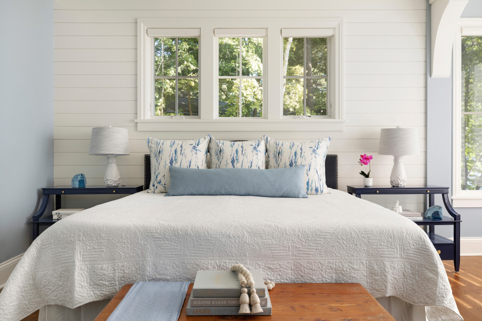 Foto de dormitorio principal costero grande con paredes azules, suelo de madera en tonos medios y suelo marrón