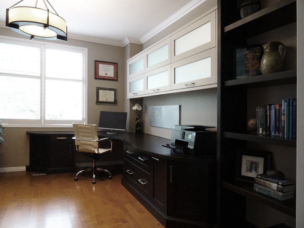 This is an example of a mid-sized contemporary study room in Toronto with beige walls, light hardwood floors and a built-in desk.