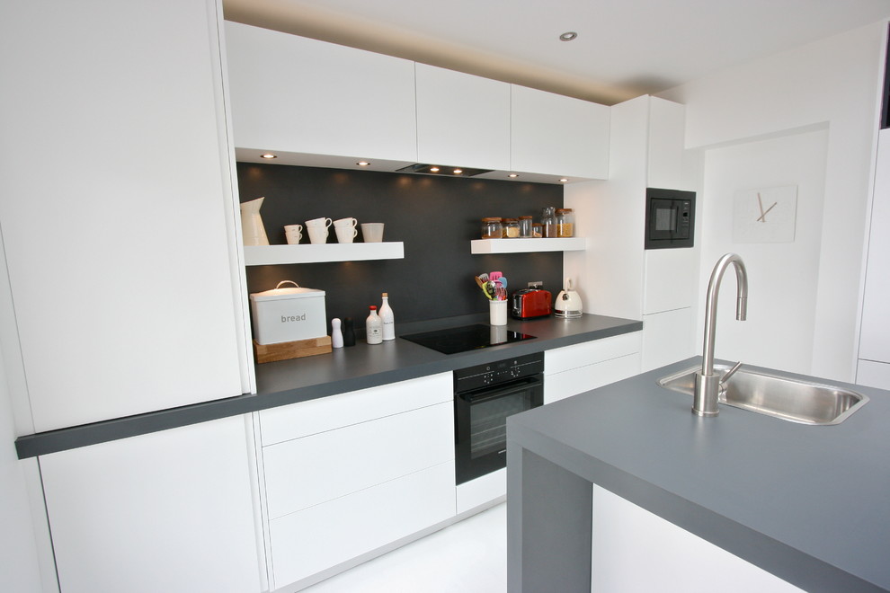 Inspiration for a medium sized modern l-shaped kitchen/diner in London with a built-in sink, flat-panel cabinets, white cabinets, laminate countertops, black appliances, white walls, an island, black splashback and painted wood flooring.