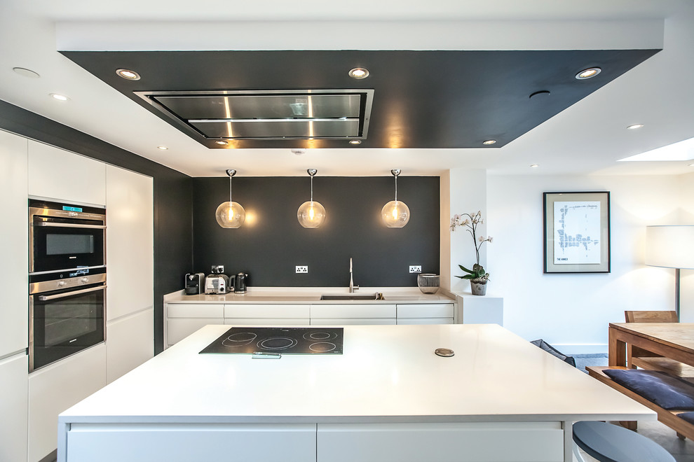 Inspiration for a large contemporary u-shaped open plan kitchen in London with an undermount sink, flat-panel cabinets, white cabinets, white splashback, stainless steel appliances and a peninsula.