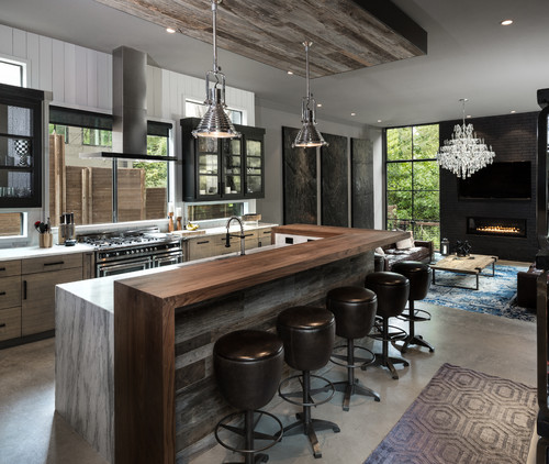 Modern open-concept kitchen with rustic wood island, marble waterfall edge, black-framed glass kitchen cabinets, pendant lights, and a cozy living area—Kitchen Cabinet Mississauga.