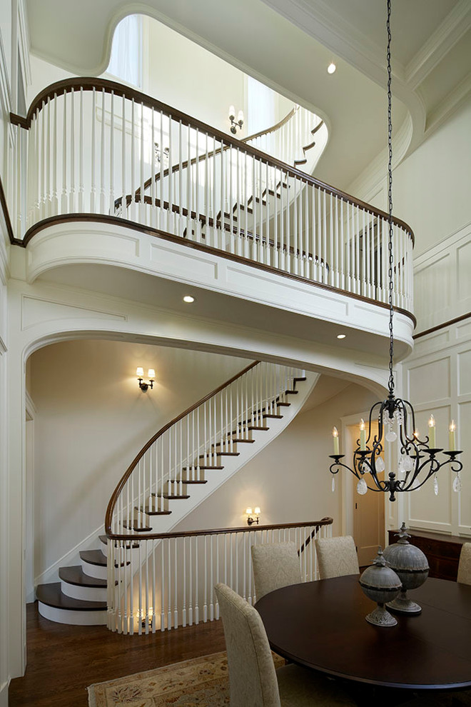 Photo of a large traditional wood curved staircase in Chicago with painted wood risers.