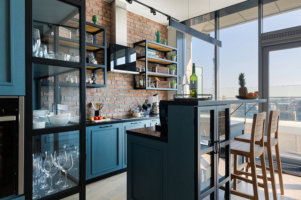 Design ideas for a large industrial galley eat-in kitchen in Saint Petersburg with an undermount sink, recessed-panel cabinets, blue cabinets, solid surface benchtops, red splashback, brick splashback, panelled appliances, medium hardwood floors, with island, beige floor and black benchtop.