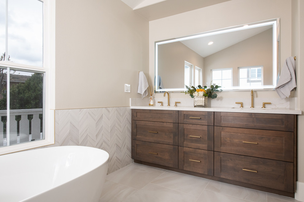 Photo of a contemporary ensuite bathroom in Orange County with flat-panel cabinets, brown cabinets, a freestanding bath, a corner shower, grey tiles, porcelain tiles, beige walls, porcelain flooring, a submerged sink, quartz worktops, white floors, a hinged door, white worktops, a wall niche, double sinks, a built in vanity unit, a vaulted ceiling and wainscoting.