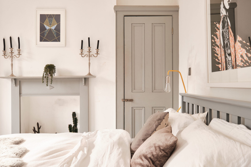 На фото: хозяйская, серо-белая спальня среднего размера в стиле фьюжн с белыми стенами, деревянным полом, стандартным камином, фасадом камина из дерева и белым полом с