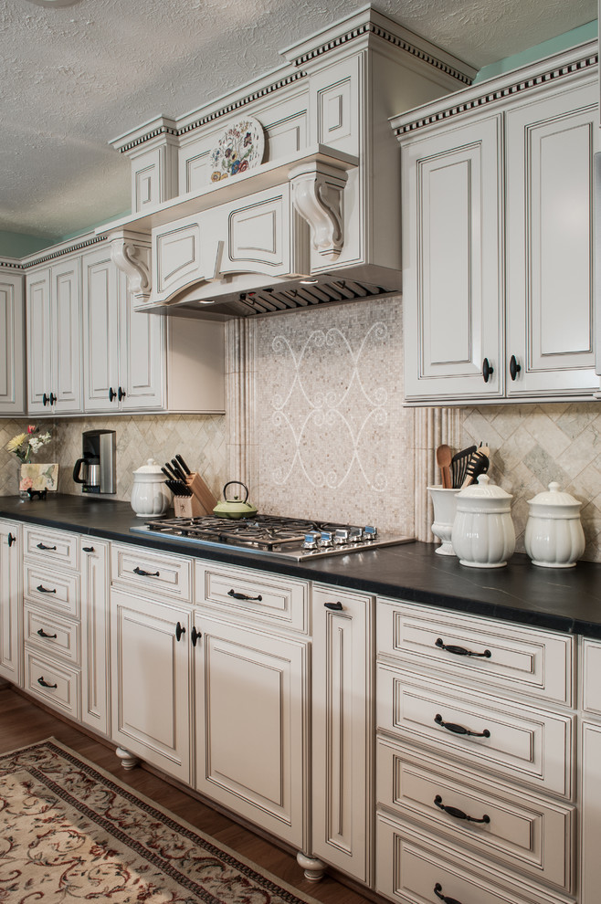 This is an example of a large traditional l-shaped eat-in kitchen in Richmond with an undermount sink, raised-panel cabinets, white cabinets, soapstone benchtops, beige splashback, mosaic tile splashback, stainless steel appliances, medium hardwood floors and with island.