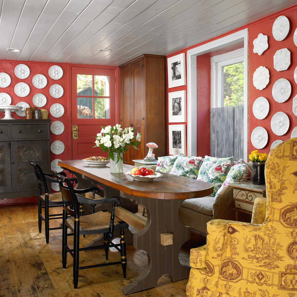 This is an example of an eclectic dining room in Philadelphia with red walls and dark hardwood floors.