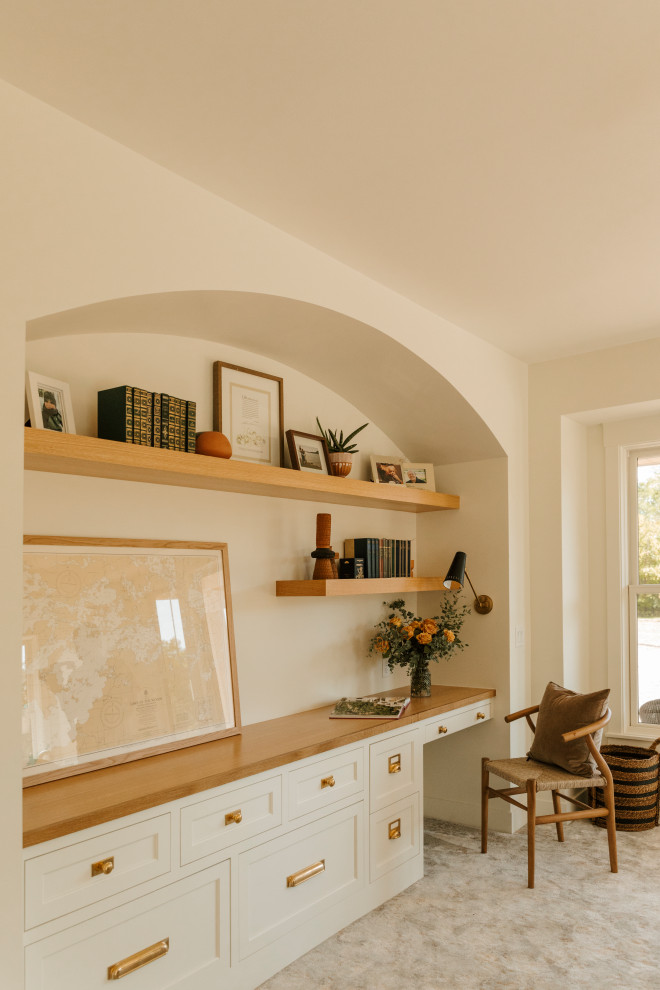 Beach style home office in Minneapolis with white walls, carpet, no fireplace, a built-in desk and beige floor.