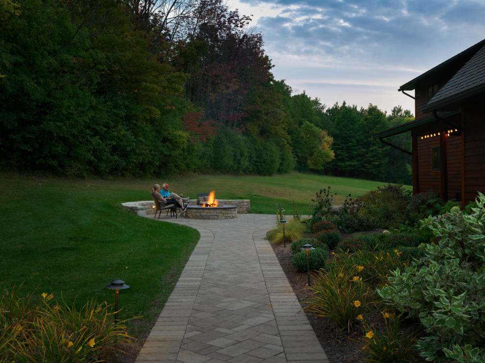 Geräumiger Landhaus Garten hinter dem Haus mit Feuerstelle, direkter Sonneneinstrahlung und Betonboden in Burlington