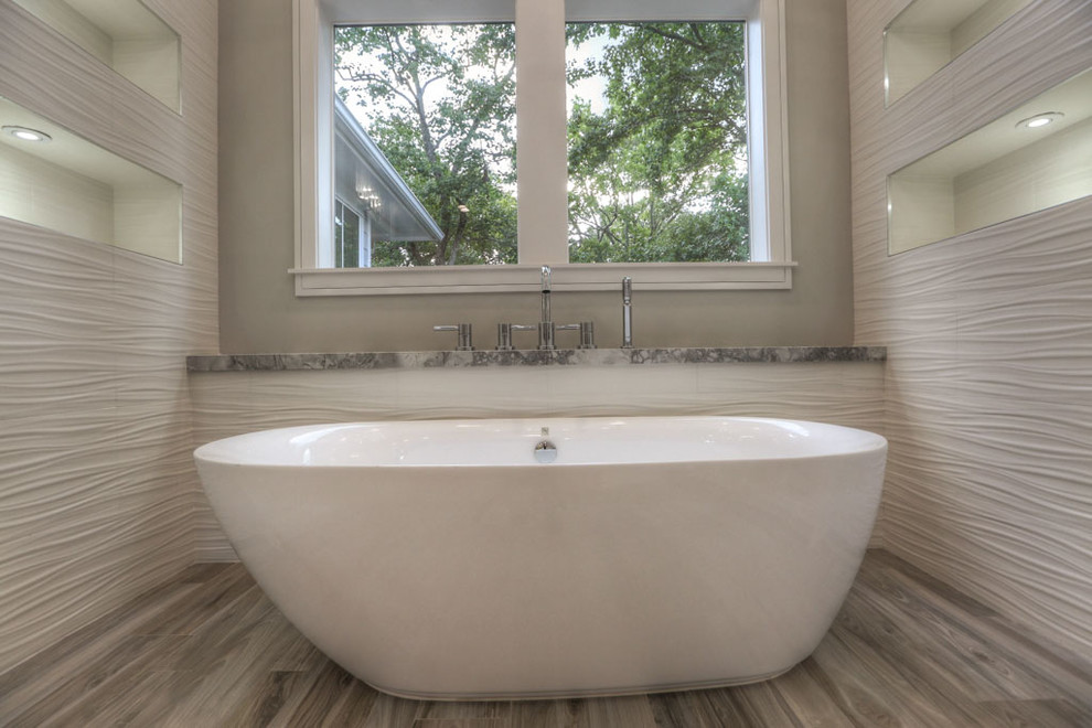 Photo of a large arts and crafts master bathroom in Houston with shaker cabinets, white cabinets, a freestanding tub, a corner shower, white tile, porcelain tile, grey walls, medium hardwood floors, an undermount sink, granite benchtops, grey floor and a hinged shower door.