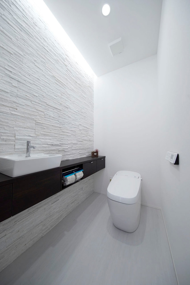 Photo of a modern powder room in Other with white walls, a vessel sink and grey floor.