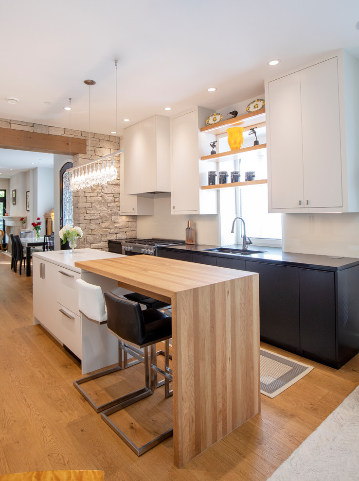 Mid-sized modern galley eat-in kitchen in Vancouver with a double-bowl sink, flat-panel cabinets, white cabinets, quartz benchtops, white splashback, glass sheet splashback, stainless steel appliances, medium hardwood floors, with island, beige floor and white benchtop.