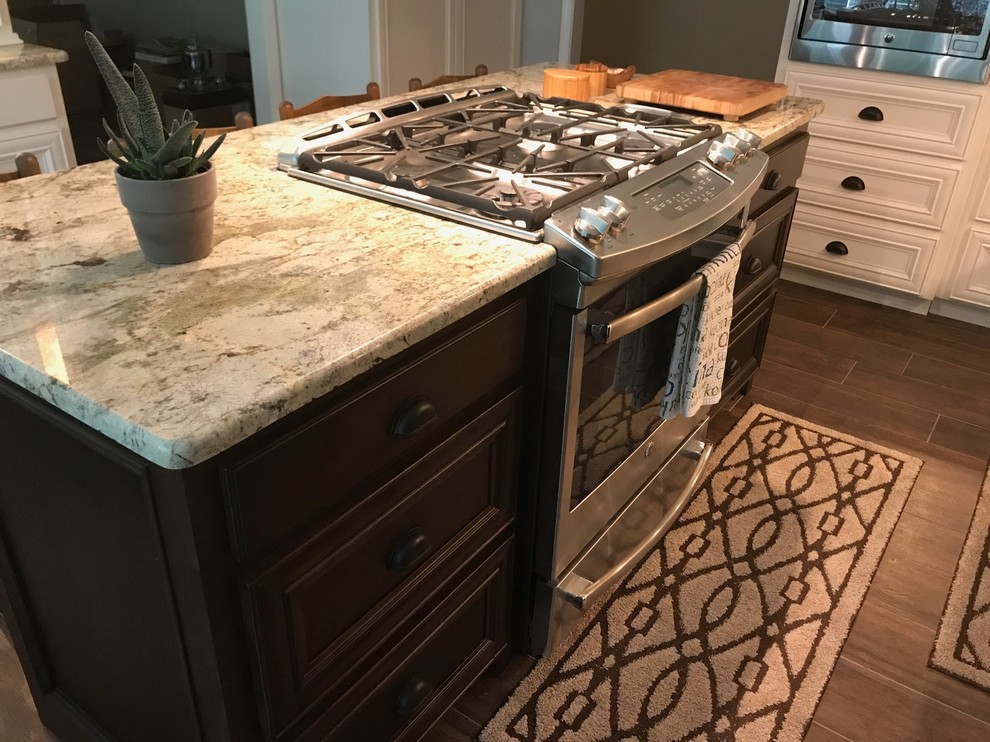Inspiration for a large transitional l-shaped brown floor eat-in kitchen remodel in Birmingham with a farmhouse sink, recessed-panel cabinets, white cabinets, beige backsplash, stainless steel appliances and an island