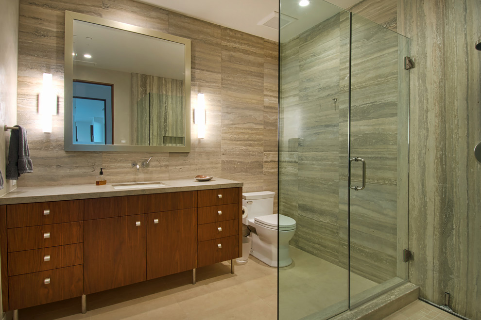 Inspiration for a contemporary 3/4 bathroom in Orange County with flat-panel cabinets, medium wood cabinets, a corner shower, a one-piece toilet, beige tile, beige walls, an undermount sink, granite benchtops, a hinged shower door and stone slab.