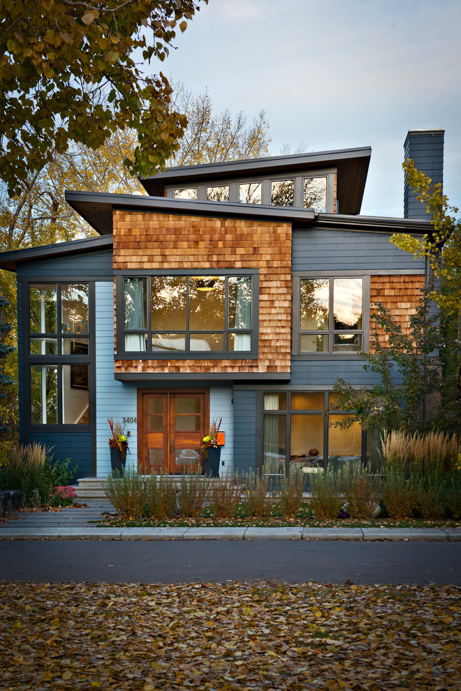 Inspiration for a large contemporary two-storey grey exterior in Calgary with vinyl siding and a flat roof.