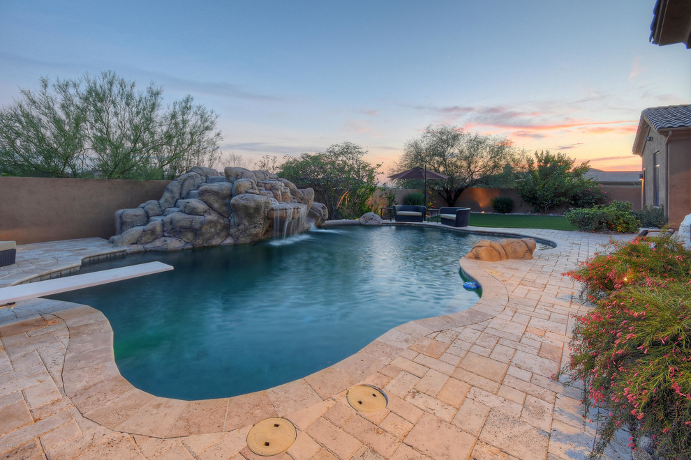 This is an example of a mid-sized backyard custom-shaped pool in Phoenix with a water slide and tile.