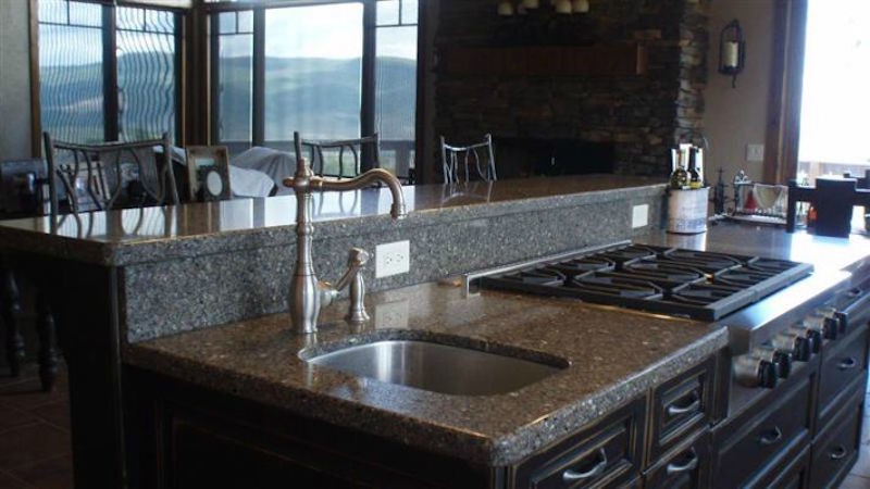 Inspiration for a kitchen remodel in Denver with raised-panel cabinets, dark wood cabinets, granite countertops, stone slab backsplash and an island