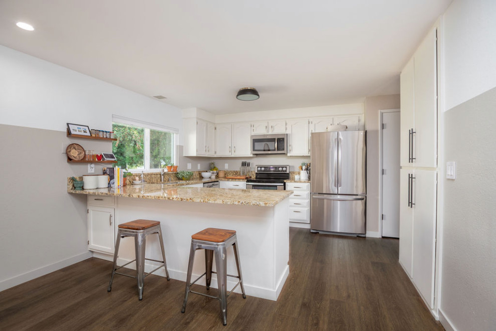 Mid-sized l-shaped eat-in kitchen in San Diego with a double-bowl sink, shaker cabinets, white cabinets, granite benchtops, grey splashback, stainless steel appliances, vinyl floors, no island, brown floor and beige benchtop.