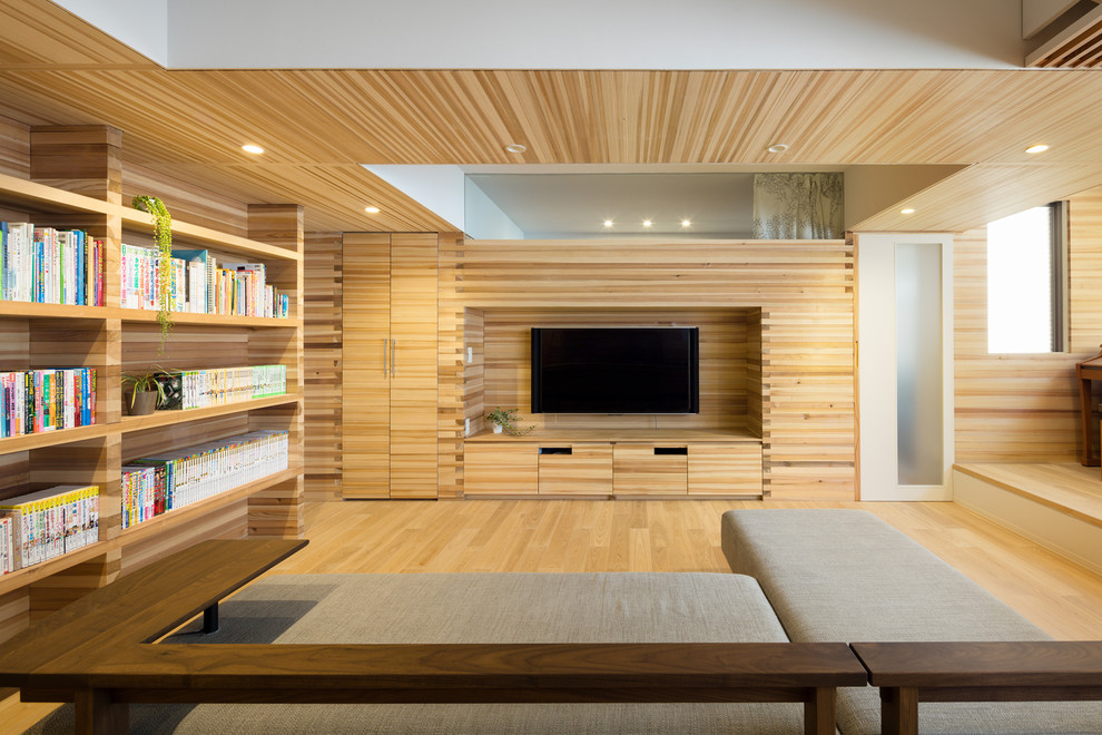 Design ideas for an asian open concept living room in Tokyo with a library, beige walls, light hardwood floors, a built-in media wall and beige floor.