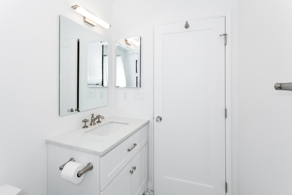 Design ideas for a mid-sized contemporary 3/4 bathroom in Los Angeles with beaded inset cabinets, white cabinets, a shower/bathtub combo, a one-piece toilet, white tile, subway tile, white walls, ceramic floors, a drop-in sink, granite benchtops, white floor, a sliding shower screen and white benchtops.