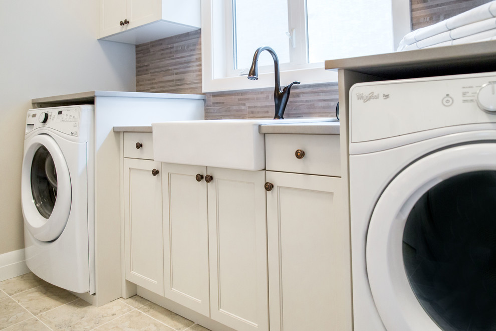 Mid-sized traditional single-wall dedicated laundry room in Calgary with a farmhouse sink, beaded inset cabinets, white cabinets, quartz benchtops and grey floor.