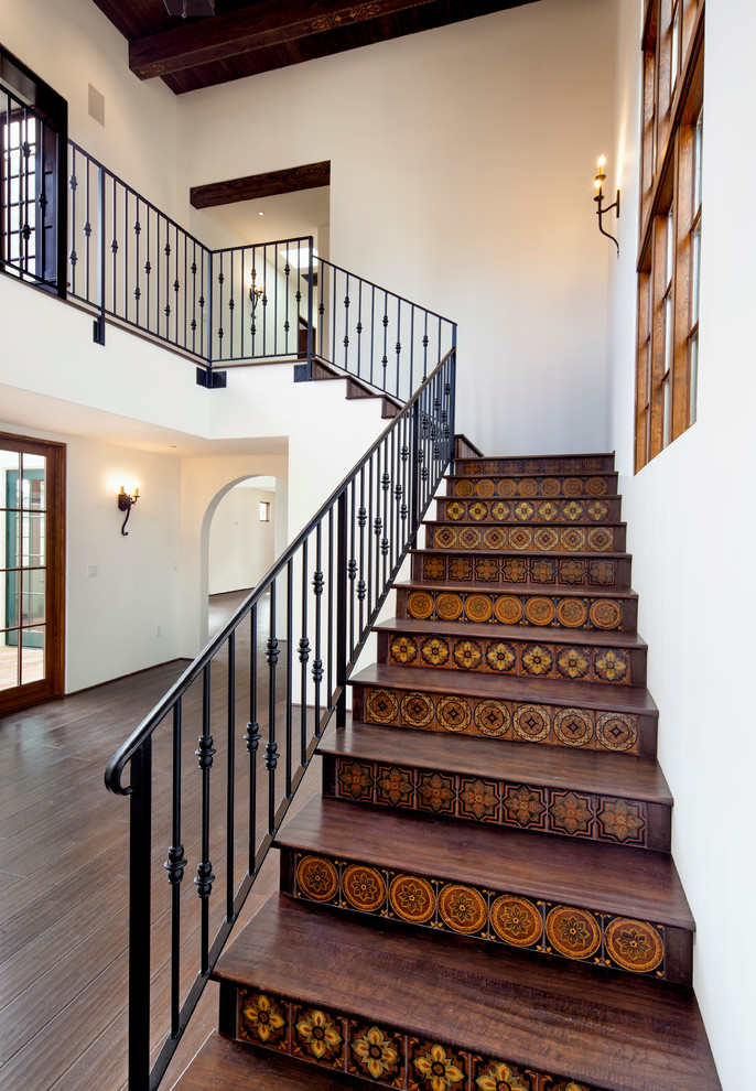 Large mediterranean wood l-shaped staircase in Santa Barbara with tile risers.