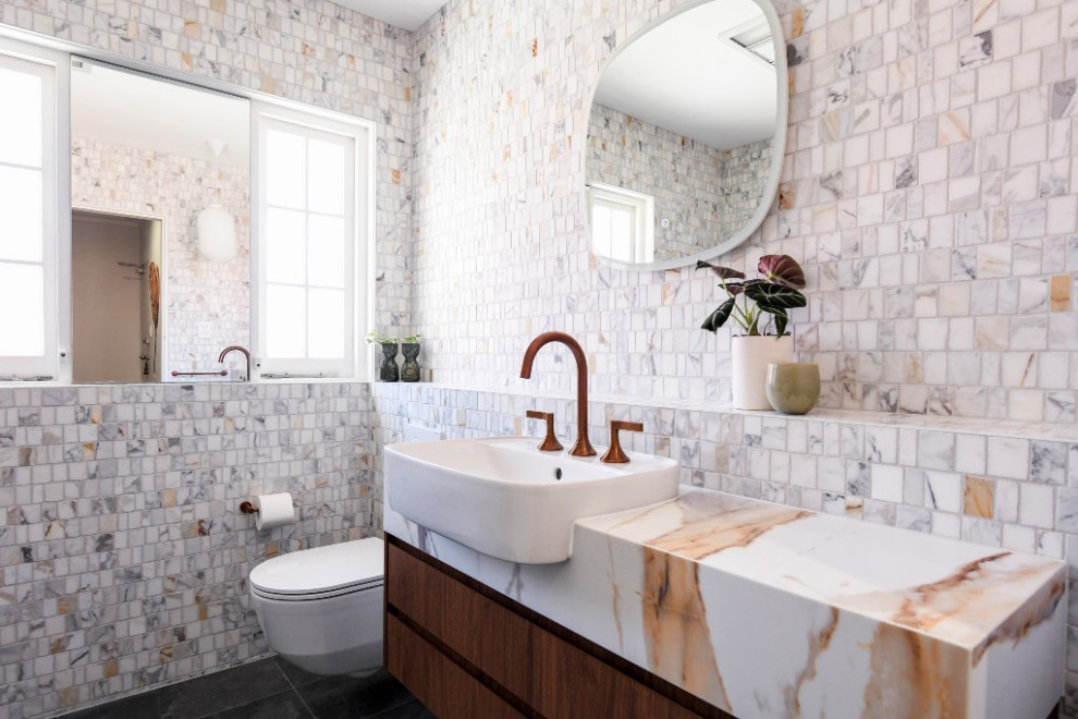 Bild på ett mellanstort 50 tals vit vitt badrum, med skåp i mellenmörkt trä, en öppen dusch, en vägghängd toalettstol, vit kakel, mosaik, vita väggar, klinkergolv i porslin, ett integrerad handfat, bänkskiva i kvarts, grått golv och med dusch som är öppen