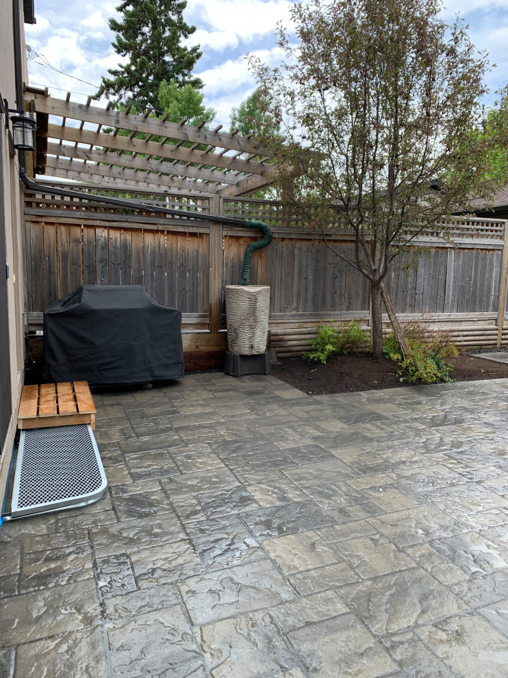 This is an example of a small classic courtyard xeriscape full sun garden for spring in Calgary with a flowerbed, brick paving and a wood fence.