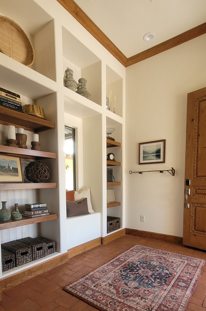 Design ideas for a large foyer in Austin with beige walls, brick floors, a single front door, a medium wood front door, brown floor and exposed beam.