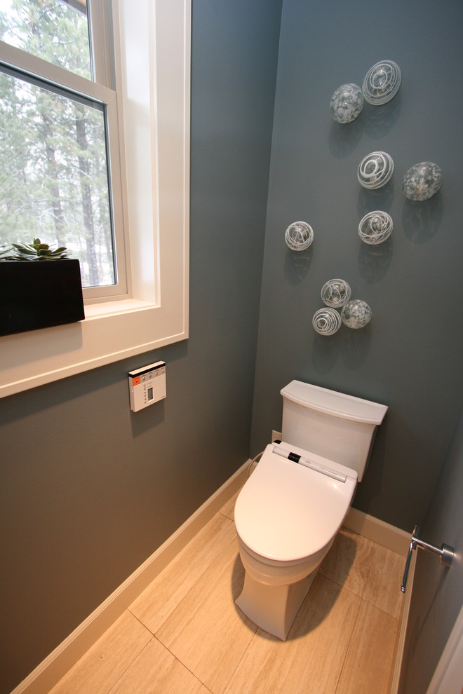 This is an example of a mid-sized contemporary powder room in Seattle with shaker cabinets, dark wood cabinets, a two-piece toilet, beige tile, stone tile, blue walls, travertine floors, a vessel sink and marble benchtops.