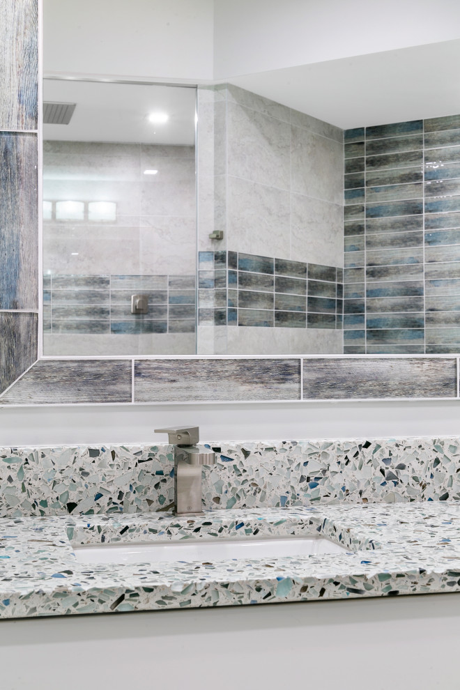 Стильный дизайн: главная ванная комната в стиле неоклассика (современная классика) с плоскими фасадами, серыми фасадами, унитазом-моноблоком, разноцветной плиткой, керамогранитной плиткой, серыми стенами, полом из керамогранита, врезной раковиной, серым полом, открытым душем, сиденьем для душа, встроенной тумбой, угловой ванной, открытым душем, столешницей терраццо, разноцветной столешницей и тумбой под две раковины - последний тренд