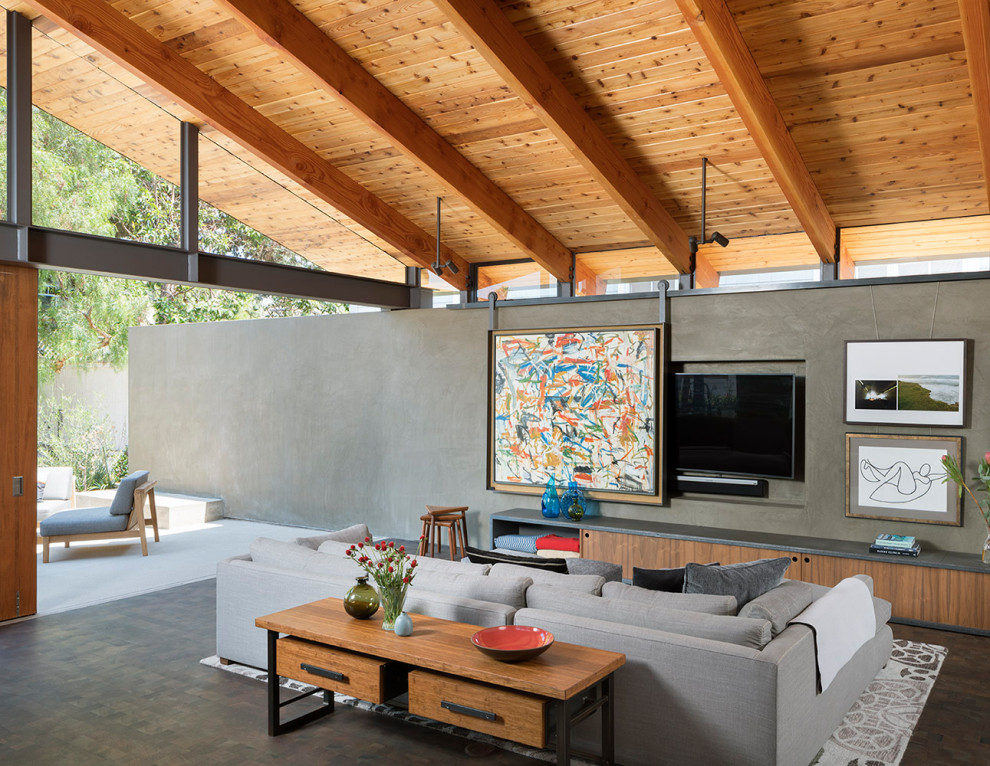 This is an example of a contemporary open concept living room in Los Angeles with grey walls, dark hardwood floors, a concealed tv, brown floor, exposed beam, vaulted and wood.