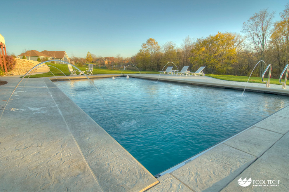 Example of a large mountain style backyard stamped concrete and rectangular pool fountain design in Cedar Rapids