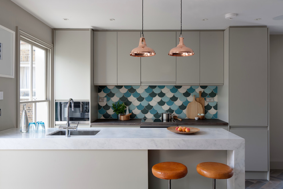 Design ideas for a contemporary galley kitchen in London with an undermount sink, flat-panel cabinets, grey cabinets, marble benchtops, blue splashback, stainless steel appliances, dark hardwood floors and a peninsula.