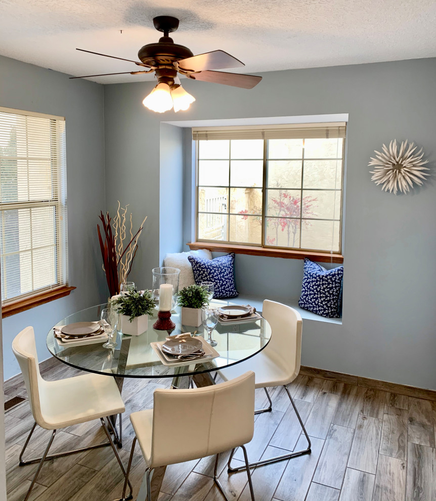 Cette photo montre une grande salle à manger tendance avec une banquette d'angle, un mur bleu, un sol en carrelage de porcelaine et un sol gris.