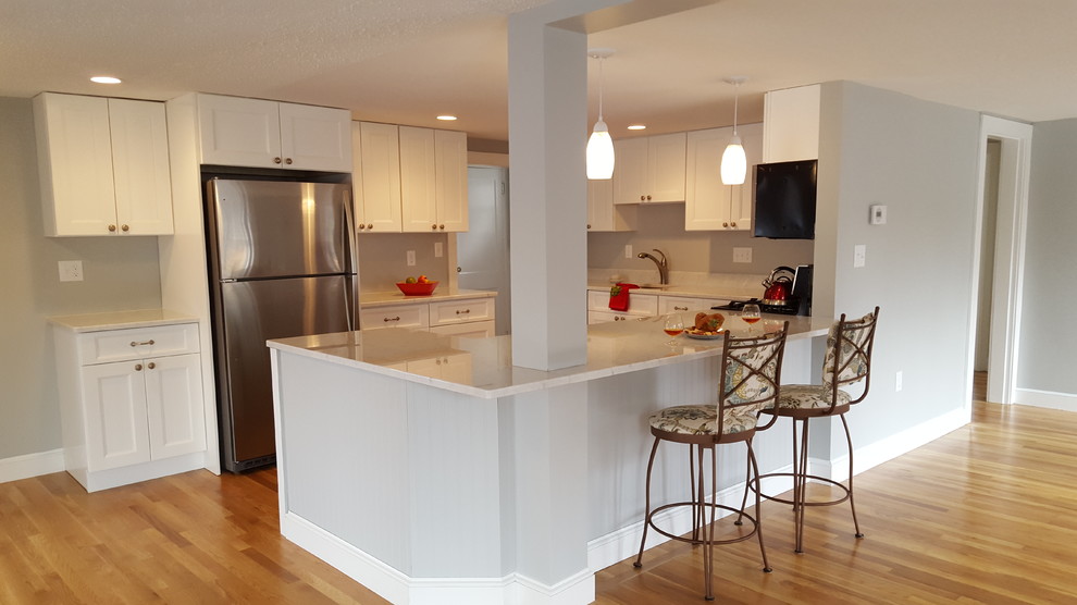 Photo of a mid-sized transitional u-shaped eat-in kitchen in Boston with an undermount sink, shaker cabinets, white cabinets, marble benchtops, grey splashback, stainless steel appliances, light hardwood floors and a peninsula.