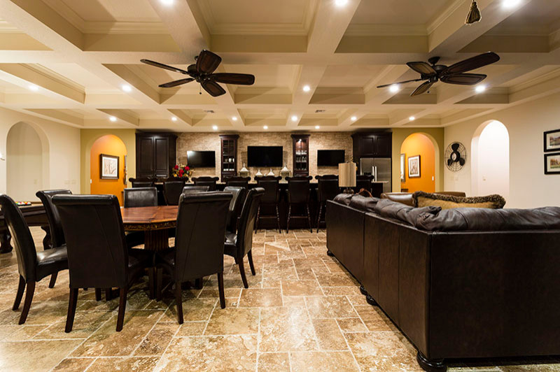 Expansive transitional single-wall seated home bar in Orlando with an undermount sink, raised-panel cabinets, dark wood cabinets, granite benchtops, beige splashback, stone tile splashback, travertine floors, beige floor and beige benchtop.