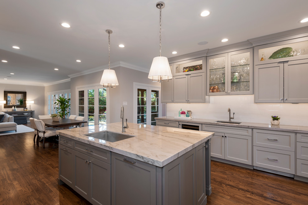Transitional u-shaped eat-in kitchen in Dallas with a single-bowl sink, raised-panel cabinets, grey cabinets, marble benchtops, white splashback, subway tile splashback, stainless steel appliances, medium hardwood floors, with island and brown floor.