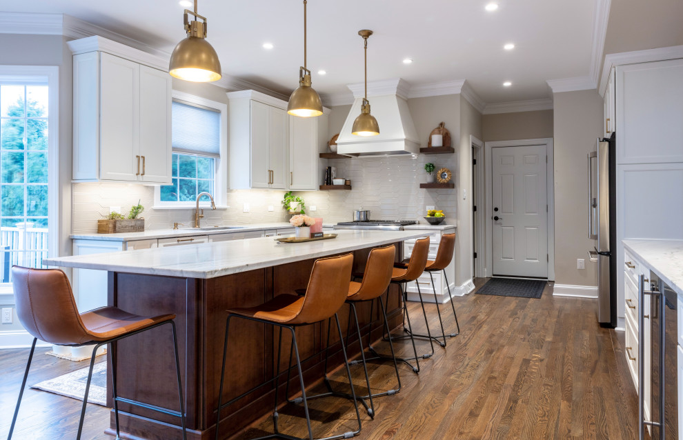 Example of a transitional medium tone wood floor kitchen design with shaker cabinets, quartzite countertops, stainless steel appliances and an island