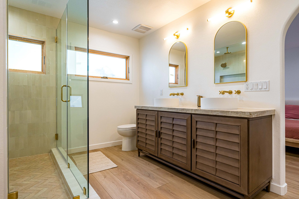 Modern inredning av ett brun brunt badrum, med ljust trägolv, brunt golv, luckor med lamellpanel, bruna skåp, en dusch i en alkov, en toalettstol med hel cisternkåpa, beige kakel, keramikplattor, vita väggar, ett fristående handfat, marmorbänkskiva, dusch med gångjärnsdörr och ett fristående badkar