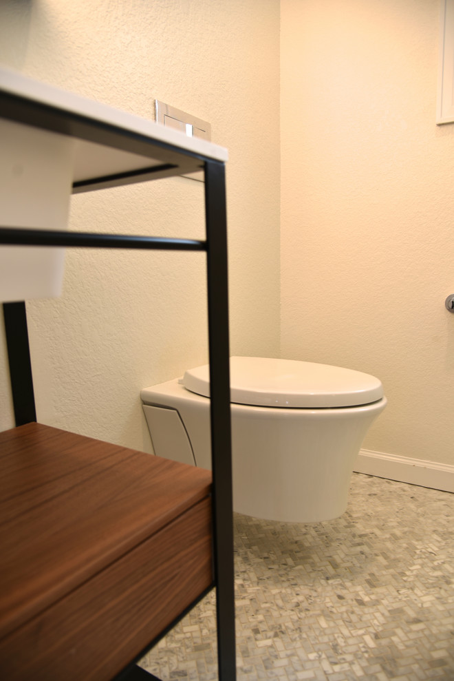 Example of a small transitional 3/4 white tile and porcelain tile marble floor and gray floor bathroom design in Denver with open cabinets, black cabinets, a wall-mount toilet, gray walls, an integrated sink, solid surface countertops, a hinged shower door and white countertops
