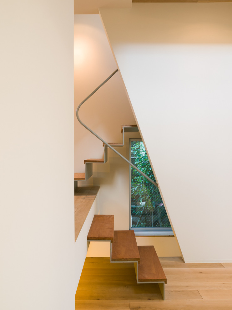 Photo of a contemporary wood staircase in Tokyo with metal risers and metal railing.